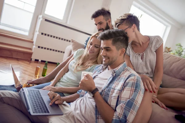 Kahve içme ve dizüstü evde oturma odası kullanan arkadaşlar gülümseyen.