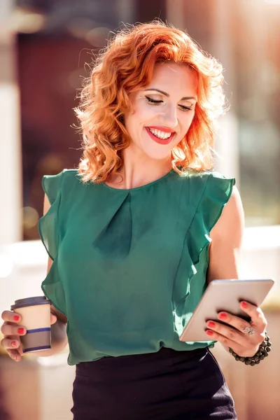 Businesswoman using digital tablet and holding coffee cup