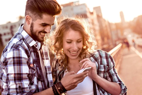 Sonriente joven pareja mirando el teléfono móvil — Foto de Stock