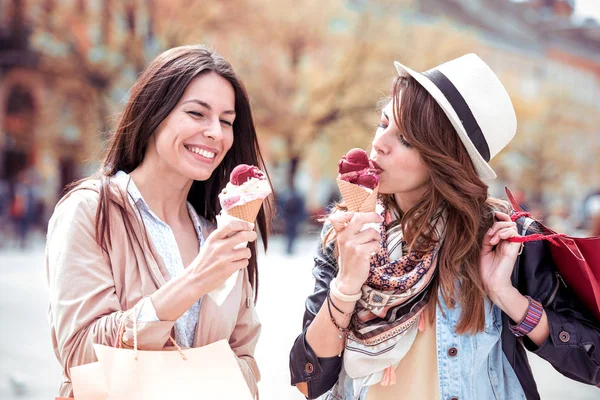 Due belle ragazze che mangiano gelato e fanno shopping . — Foto Stock