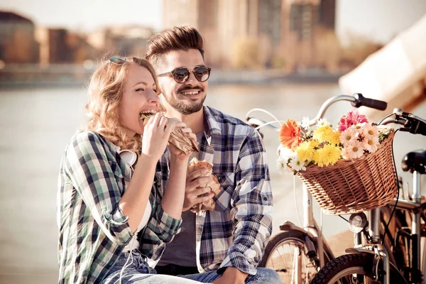 Pareja Romántica Sentada Comiendo Sándwich Con Río Sobre Fondo — Foto de Stock