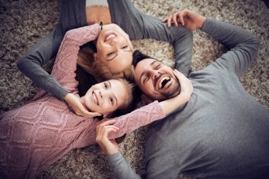Yerde yatarken kameraya gülümseyen mutlu genç ailesinin Üstten Görünüm.