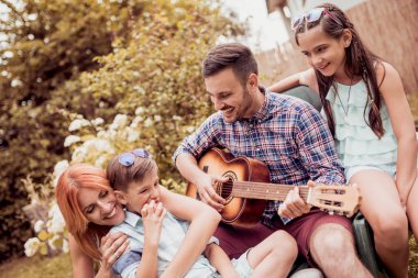 Genç aile bahçesinde gitar çalma kalitesi zaman zevk.