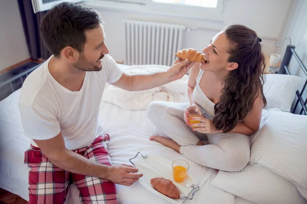 Jovem casal bonito tomando café da manhã na cama . — Fotografia de Stock