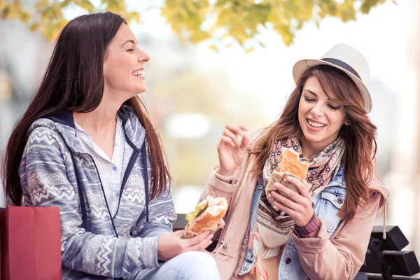 Duas meninas bonitas comer sanduíche depois de fazer compras . — Fotografia de Stock