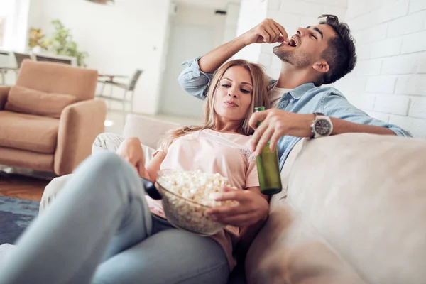 若いカップルがソファでリラックスとポップコーンを食べて — ストック写真