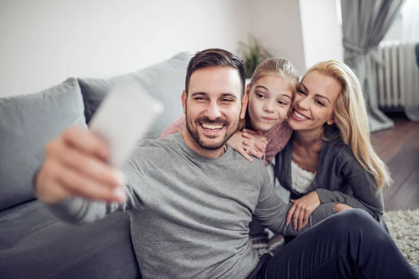 Laughing family taking selfie with smart phone at home.