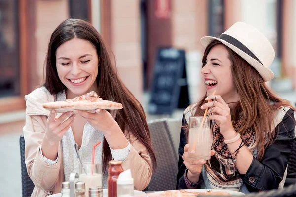 Két mosolygó lány kávézóban pizzát eszik. — Stock Fotó