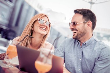 Bir kafede dizüstü kullanarak ve eğlenerek mutlu çift.