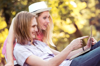 Genç çift dışarıda dizüstü bilgisayar kullanıyor..