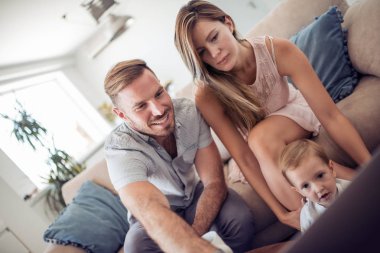 Dizüstü bilgisayar kullanan evde mutlu bir aile portresi. Oğlu ve veliler ile bir dizüstü bilgisayar oynamak.