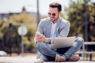 Dışarıda, cep telefonu kullanarak genç çekici adam.