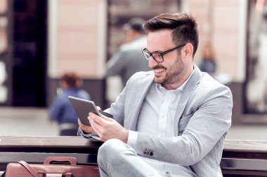 Genç işadamı şehirde bir bankta tablet kullanma