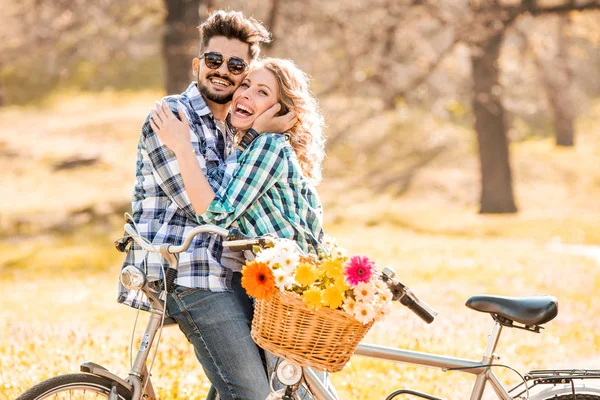 Pareja con bicicleta en un día soleado en el parque con cesta de flores . — Foto de Stock