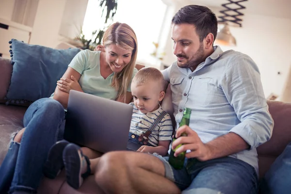 Familia feliz usando el ordenador portátil juntos en el sofá en casa. — Foto de Stock