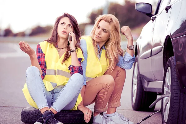 Дві дівчини на дорозі намагаються полагодити машину — стокове фото