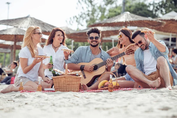 Gente feliz comiendo pizza y divertirse en la playa . — Foto de Stock