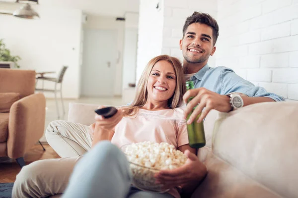 Pareja viendo televisión y comiendo palomitas de maíz . — Foto de Stock