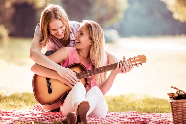 Young woman plays the guitar her boyfriend. — Stock Photo, Image