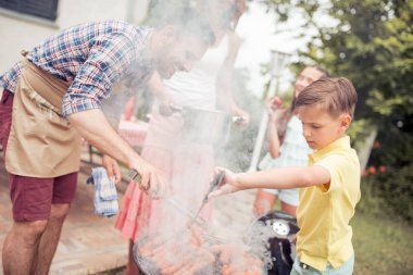 Gülümseyen adam ailenizle, hafta sonu arka bahçesinde zevk Barbekü yemek pişirme.
