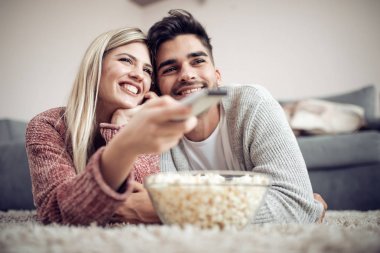 Genç çift dairelerinde rahatlatıcı, kanepede yatan, bir film seyrederken ve patlamış mısır yemek.