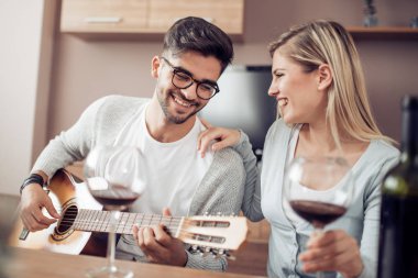 yakışıklı bir adam kız arkadaşını evde oturma odasında gitar ile serenat