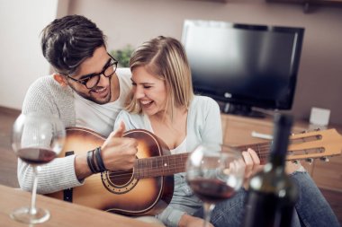 yakışıklı bir adam kız arkadaşını evde oturma odasında gitar ile serenat