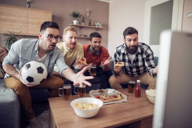 Pizza yeme ve soğuk bira içme sırasında evde TV izlerken arkadaşlar.
