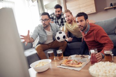 Pizza yeme ve soğuk bira içme sırasında evde TV izlerken arkadaşlar.