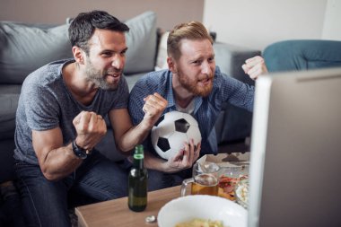 Pizza yeme ve soğuk bira içme sırasında evde TV izlerken arkadaşlar.