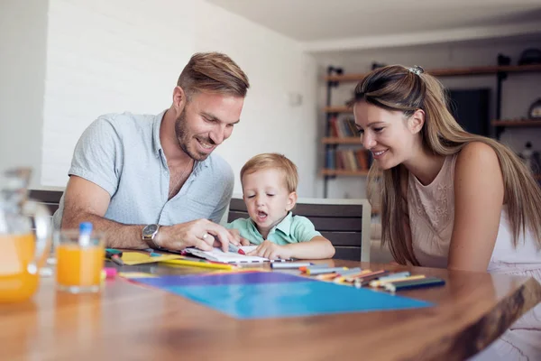 ママとパパと彼らの息子を描きます Mom ノートに何かを示しています — ストック写真