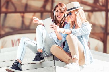 İki genç güzel kız şehirde oturan ve müzik.