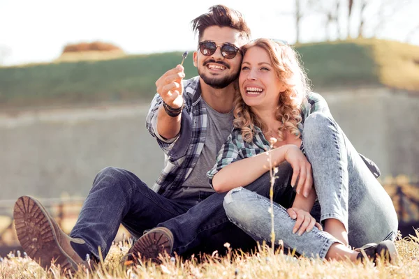 Pareja Joven Sentada Hierba Mirando Hacia Otro Lado Sonriendo Hombre — Foto de Stock