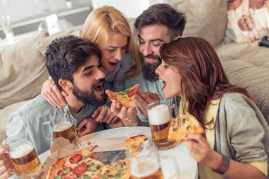 Pizza yiyip evde bira içmeyi gülümseyen arkadaşlar