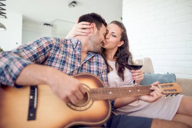 Oturma odasında, dinleme ve erkek öpüşme kadın gitar çalmak adam