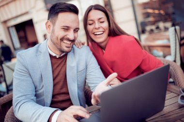 Genç çift kafede otururken dizüstü bilgisayar kullanarak