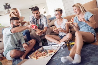 Pizza yiyip evde bira içmeyi mutlu genç arkadaş grubu