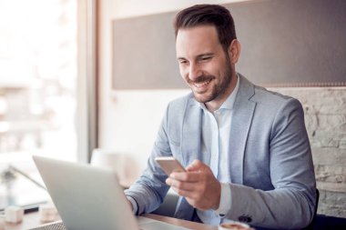 dizüstü bilgisayar kullanan işyerinde rahat gömlekli genç işadamı