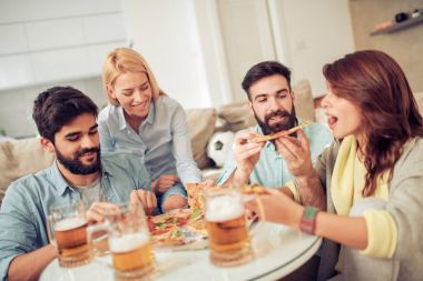 Pizza yiyip evde bira içmeyi gülümseyen arkadaşlar