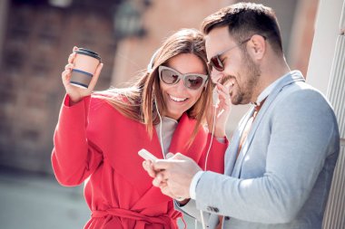 Mutlu çift kulaklık smartphone sokakta müzik paylaşımı ile