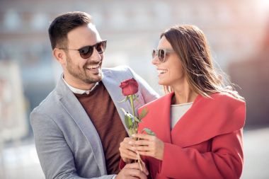 Man and woman with red rose in city