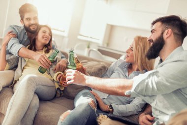 Neşeli grup arkadaşıyla birlikte kanepede bira içmek