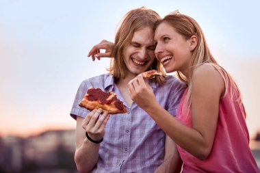 Genç çift açık havada oturma ve pizza yemek