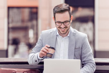 dizüstü bilgisayar ve kahve ile oturan genç adam