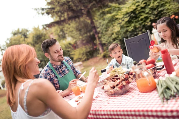 Happy young family having lunch barbecue in garden on sunny day