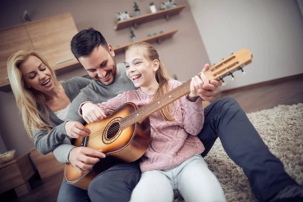 Father playing guitar for wife and daughter