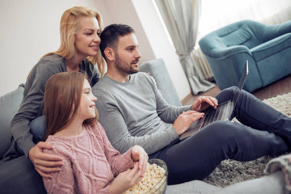 Happy family watching movie on laptop at home