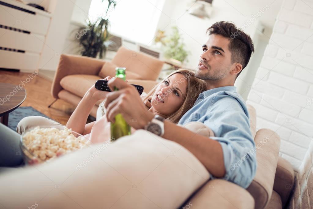 Young couple watching movie and eating popcorn
