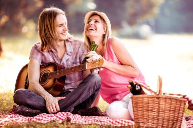 Piknik zamanı. Genç çift gitar ile Parkta piknik üzerinde eğleniyor. Sevgi ve şefkat, yaşam kavramı.