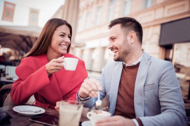 Genç çift birlikte bir şehir kafede otururken eğleniyor. Bir fincan kahve bir tarihte sahip çift.